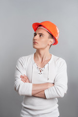 Portrait of a young confident worker in helmet isolated on grey
