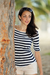 Young woman posing behind an old tree