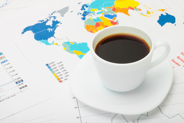 Coffee cup above world map and some financial documents