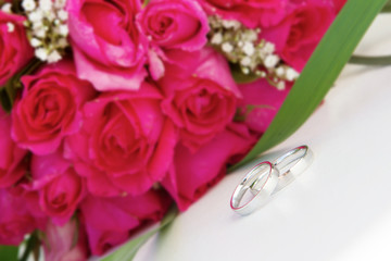 wedding rings and bridal bouquet over white