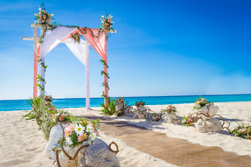 wedding arch decorated with flowers on tropical sand beach, outd