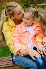 happy mother hugs her daughter on bench