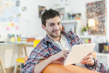 young student lying on a couch surfing  the web  on his digital
