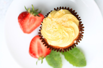 A lemon cake on white plate with strawberries, close up