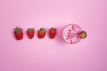 Fresh strawberry smoothie and strawberries on pink background