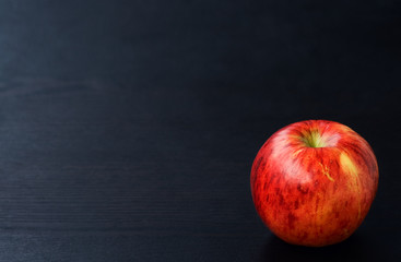 Fototapeta na wymiar Red apple on black wooden background