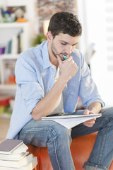 young student sits on a sofa is writing on a notebook