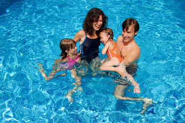 Happy family having fun in swimming pool on vacation