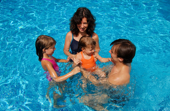 Happy family having fun in swimming pool on vacation