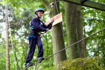 Happy boy enjoying a climbing adventure in activity park