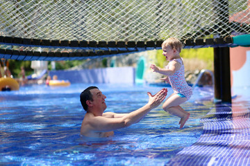 Active father having fun in swimming pool with his daughter