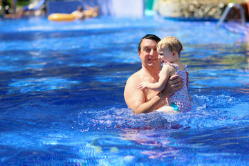 Active father having fun in swimming pool with his daughter