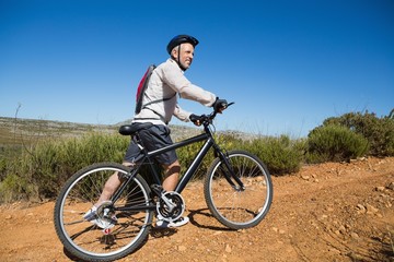 Fototapeta na wymiar Fit cyclist pushing bike uphill on country terrain