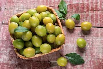 Yellow plums in a basket on wooden background