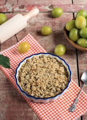 Plum crumble with cream on wooden background