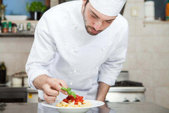 Male chef completing pasta.