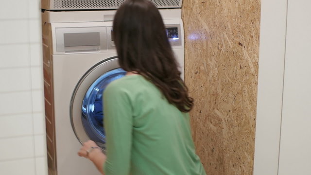 woman takes a shirt out of a washing machine it's still dirty