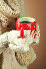 Female hands with hot drink, on color background