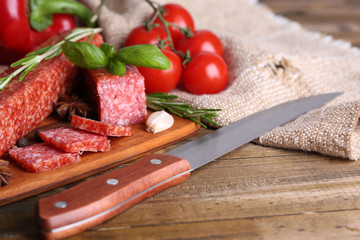 Tasty salami sausage and spices on wooden background