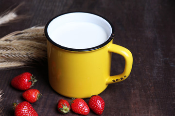 Ripe sweet strawberries in wooden bowl and mug with milk