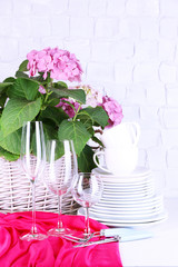 Blooming hydrangea and utensils on table on grey wall