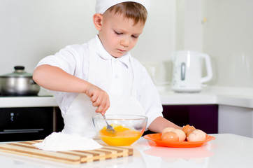 Young boy baking whipping eggs