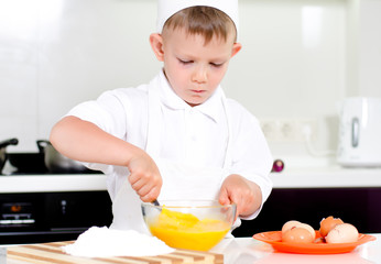 Young boy baking whipping eggs