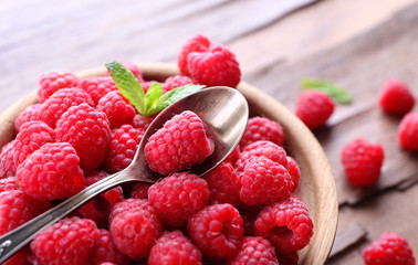 Ripe sweet raspberries in bowl on table close-up