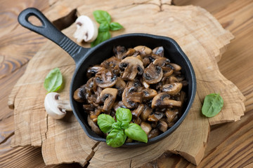 Frying pan with roasted champignons and green basil, studio shot