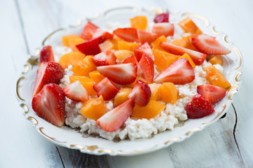 Glass plate with cottage cheese and fresh fruits, close-up