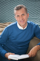 Man reading book in sofa and smiling