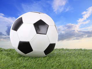 Fototapeta na wymiar Stitch leather soccer ball on green field blur sky.