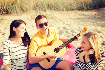 group of friends with guitar having fun on beach