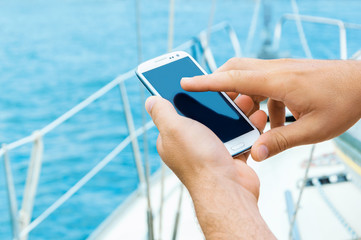Male hands holding smartphone on sailing