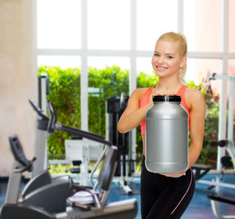 Fototapeta premium smiling sporty woman with jar of protein
