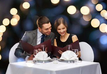 smiling couple with menus at restaurant