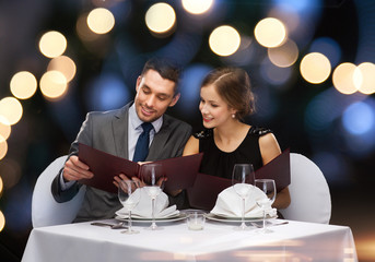 smiling couple with menus at restaurant