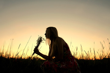 Silhouette of Girl Picking Flowers in Meadow at Sunset - Powered by Adobe