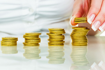 Frau mit Münzstapel beim Geld sparen