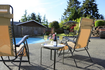 Backyard with swimming pool, wine and chairs.