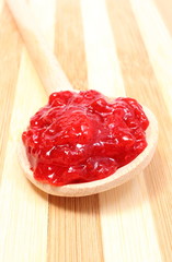 Strawberry jam with wooden spoon on cutting board