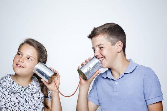 Kids speaking to a can against gray background