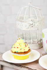 Tasty cup cake with cream on wooden table