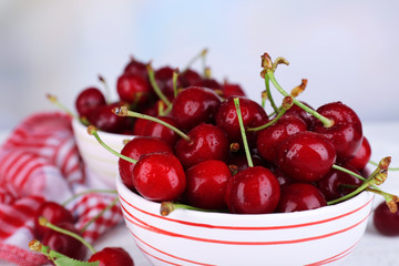 Ripe sweet cherries in bowl on wooden table