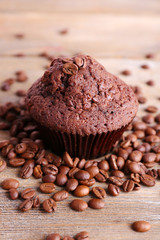 Chocolate muffin and coffee grains on wooden background