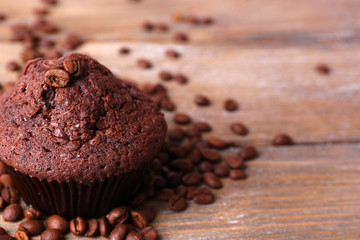 Chocolate muffin and coffee grains on wooden background