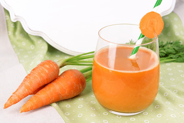 Glass of carrot juice and fresh carrots on table close up