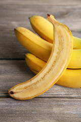 Halved and whole ripe bananas on wooden background