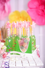 Bottles of drink with straw and sweets on decorative background