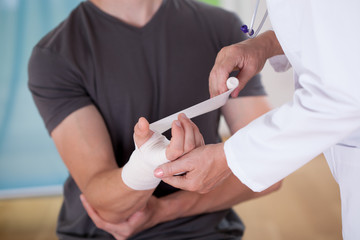 Doctor parceling patient's wrist